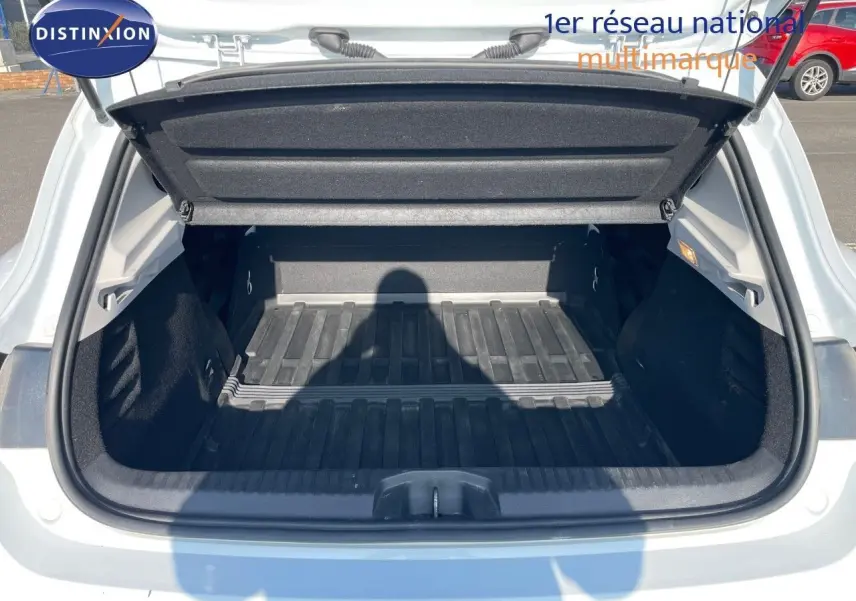 Coffre ouvert vu de l'arrière d'une Renault Clio Société blanc glacier, montrant l'espace de chargement vide et sa protection.