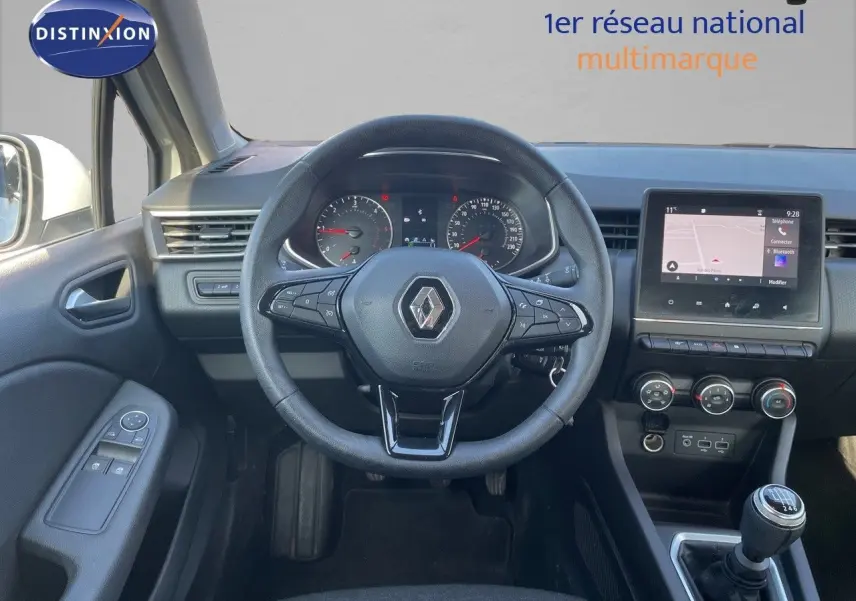 Vue intérieure centrée sur le volant Renault avec tableau de bord, écran tactile et levier de vitesse manuel.