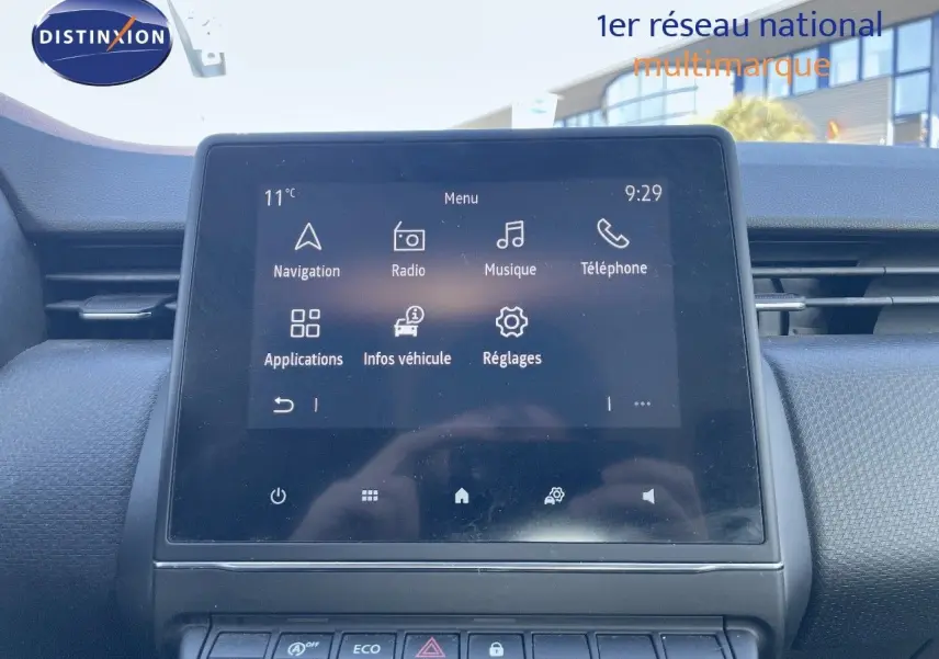 Écran tactile central allumé du tableau de bord d'une Renault Clio Société blanche, vue intérieure frontale.