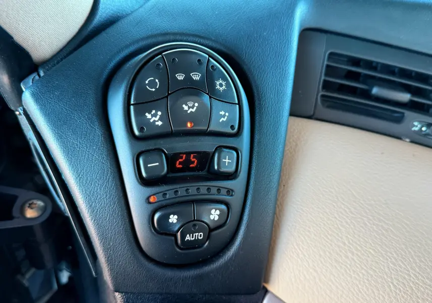 Gros plan sur la commande de climatisation digitale du tableau de bord noir et beige d'une Renault Avantime gris.