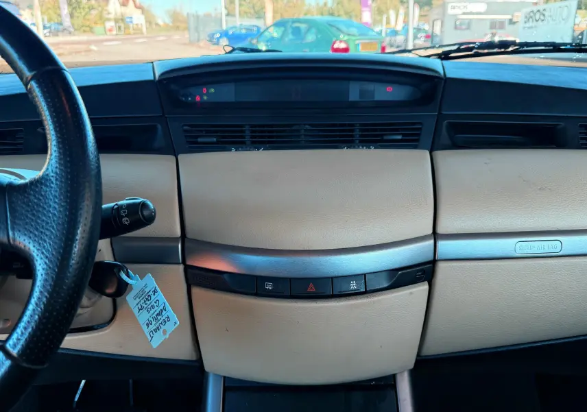 Tableau de bord beige et noir vu de face dans une Renault Avantime gris, avec volant à gauche et commandes centrales visibles.