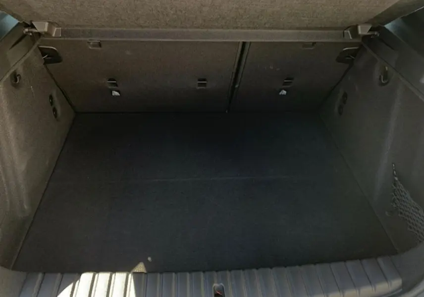 Coffre spacieux de BMW Série 1 118d M Sport noir métal, avec filet côté droit et crochets porte-sacs visibles.