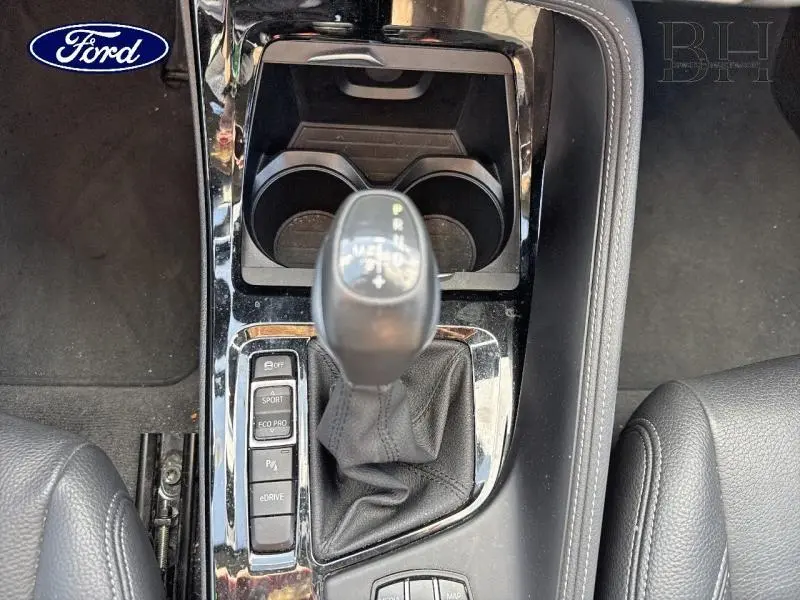 Le levier de vitesses automatique noir et la console centrale d'une BMW X1 xDrive25eA Saphirschwarz vue de dessus.