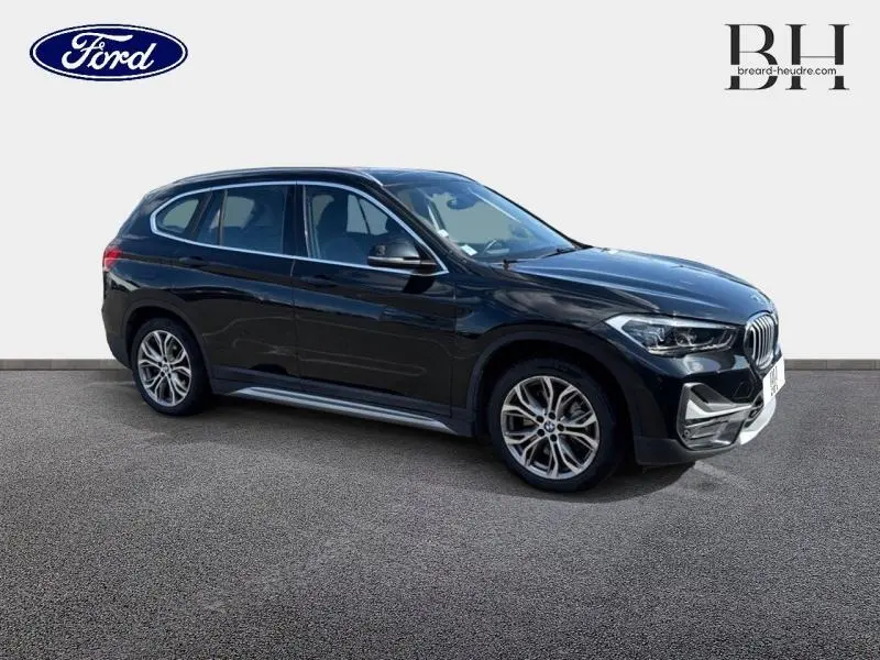 BMW X1 xDrive25e saphirschwarz vue 3/4 avant droit, mettant en valeur ses jantes alliage et calandre distinctive.
