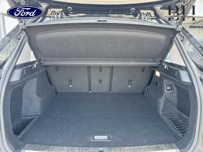Coffre ouvert vu de l'arrière d'un BMW X1 xDrive25eA 220ch xLine noir Saphirschwarz avec filet de rangement latéral.