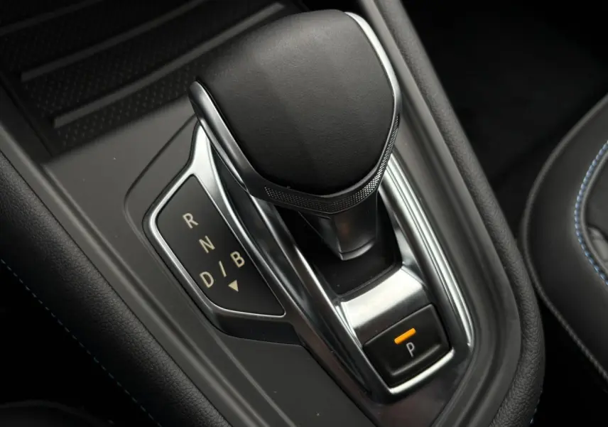 Gros plan sur le levier de vitesses automatique noir et chrome du Renault Captur hybride, avec bouton de parking éclairé.