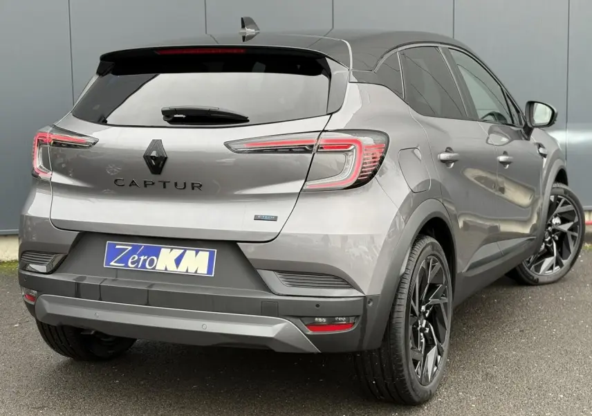 Vue 3/4 arrière droite d'un Renault Captur gris Cassiopée avec toit noir et jantes noires distinctives.