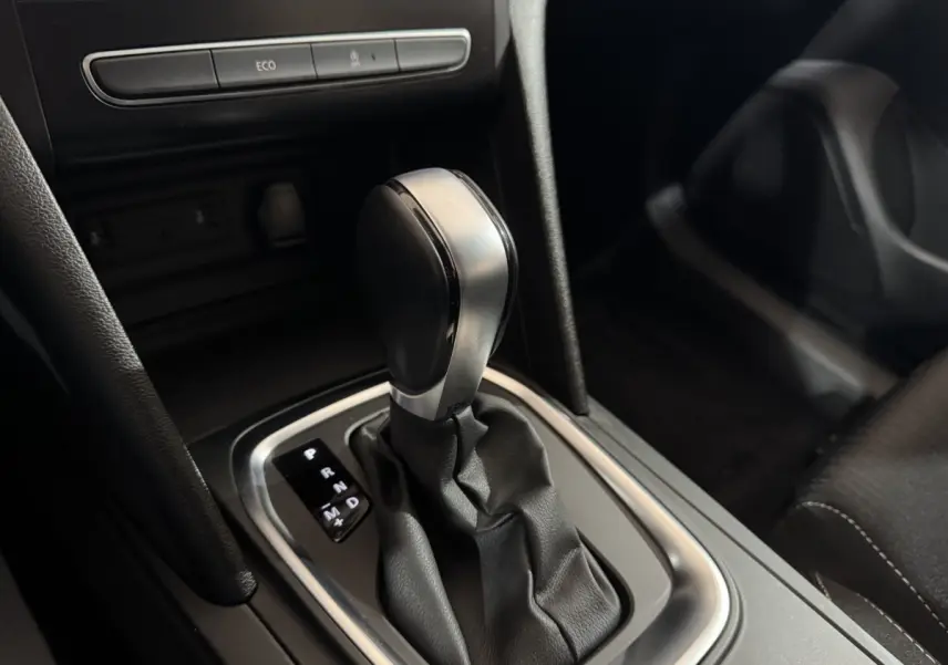 Gros plan sur la commande de boîte automatique noire et argentée dans l’habitacle sombre de la Renault Mégane Business 2019.
