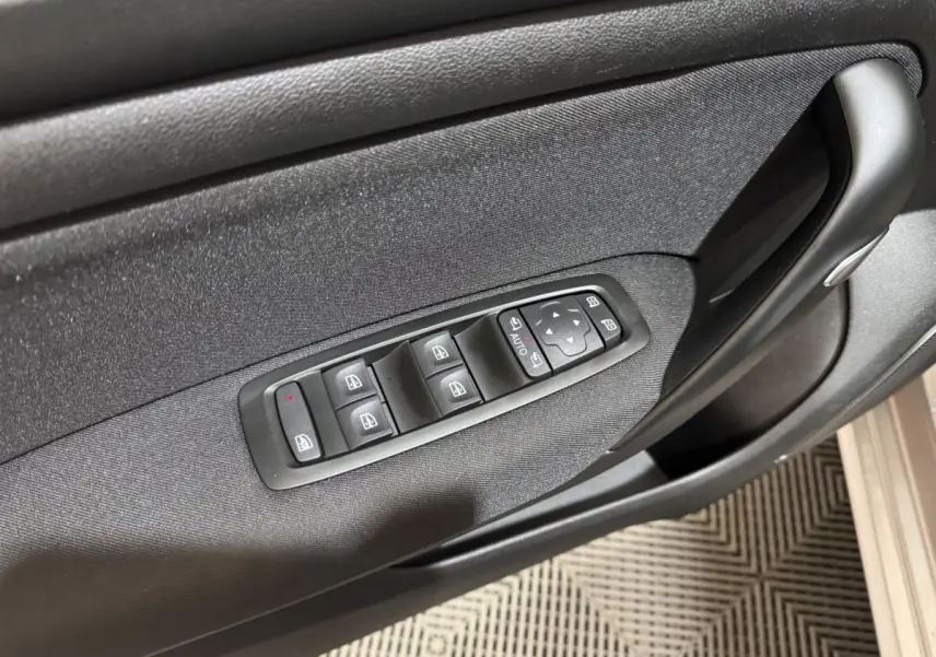 Vue rapprochée de la porte côté conducteur de la Renault Mégane Business gris clair avec commandes électriques des vitres et rétroviseurs.