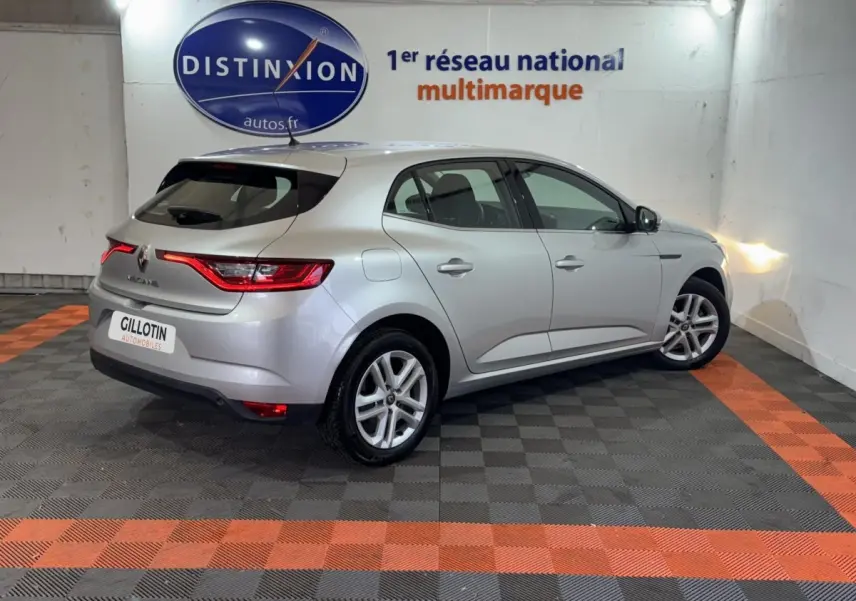 Renault Mégane Business gris clair vue 3/4 arrière droit dans un showroom avec éclairage mural.
