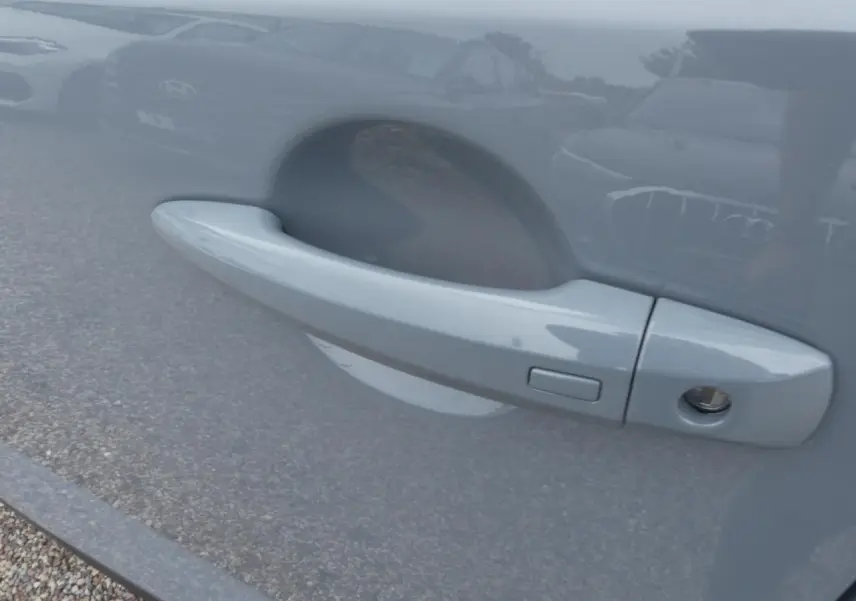 Poignée de porte côté gauche gris métallisé du Nissan Qashqai 1.5 e-Power 2025 avec bouton de déverrouillage.