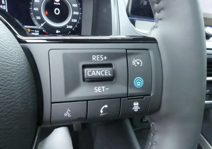Gros plan sur les commandes du régulateur de vitesse au volant cuir du Nissan Qashqai gris métallisé 2025.