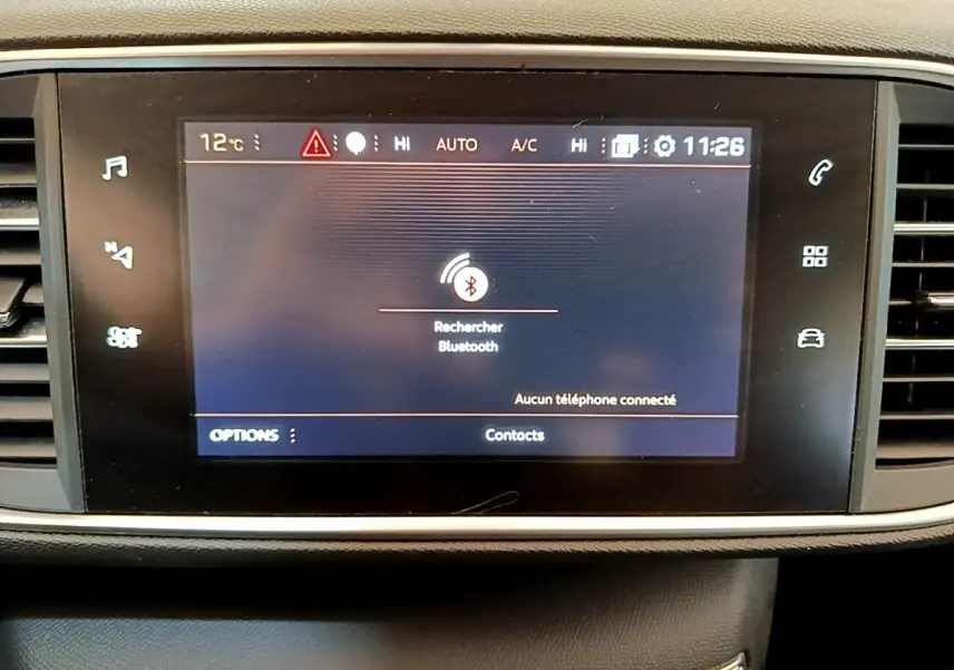 Écran tactile central de la Peugeot 308 blanc, affichant la recherche Bluetooth, entouré de commandes noires.