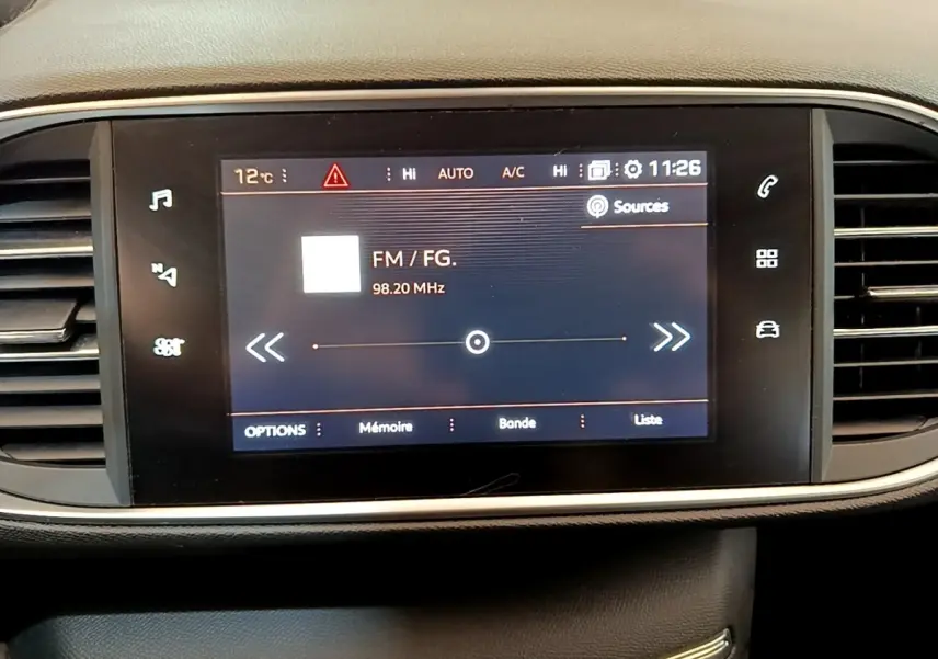 Écran tactile central de la Peugeot 308 blanc 2017 affichant la radio FM à 98,20 MHz, entouré de commandes.