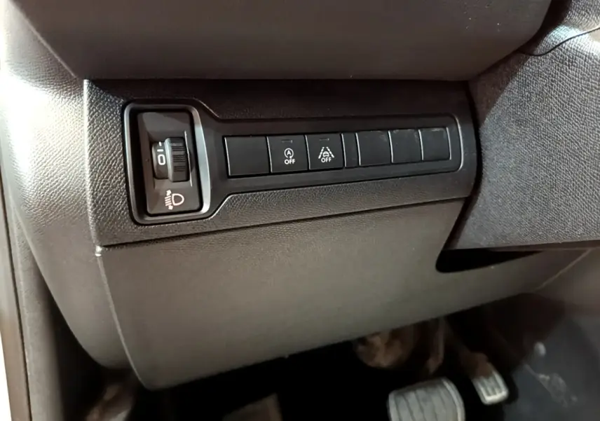 Vue intérieure côté conducteur du tableau de bord noir avec commandes d'éclairage et aides à la conduite sur Peugeot 308 blanc.