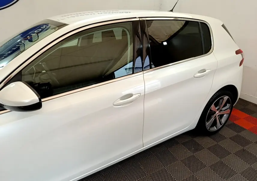 Vue latérale côté gauche d'une Peugeot 308 blanche de 2017, avec vitres teintées et jantes alliage distinctives.