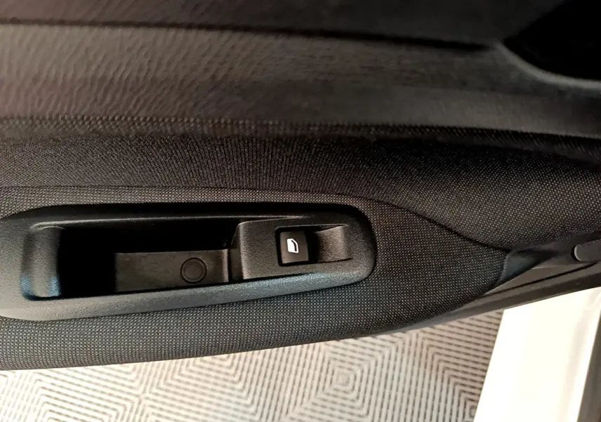 Bouton de commande de vitre sur la porte côté gauche d'une Peugeot 308 blanche vue de l'intérieur.