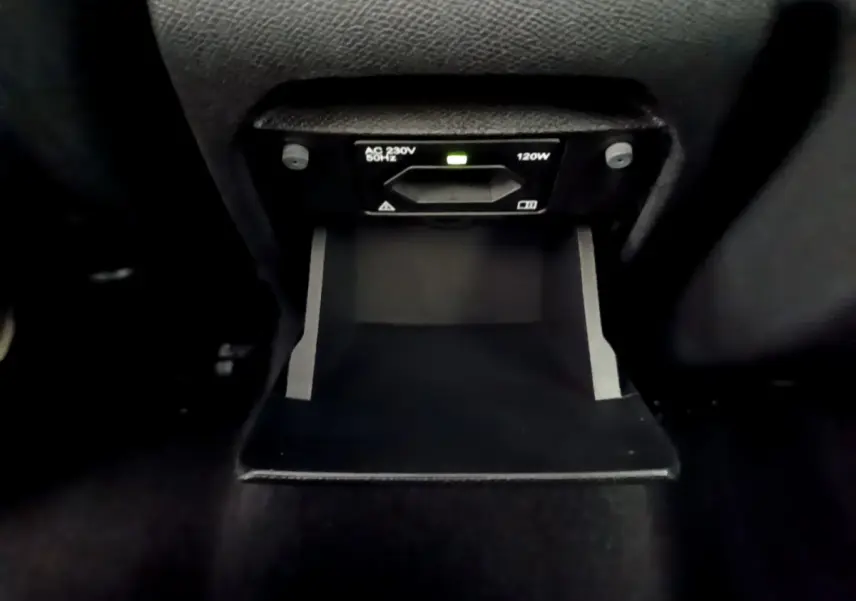 Prise électrique 230V 120W en gros plan dans l'habitacle arrière de la Peugeot 308 blanche de 2017.