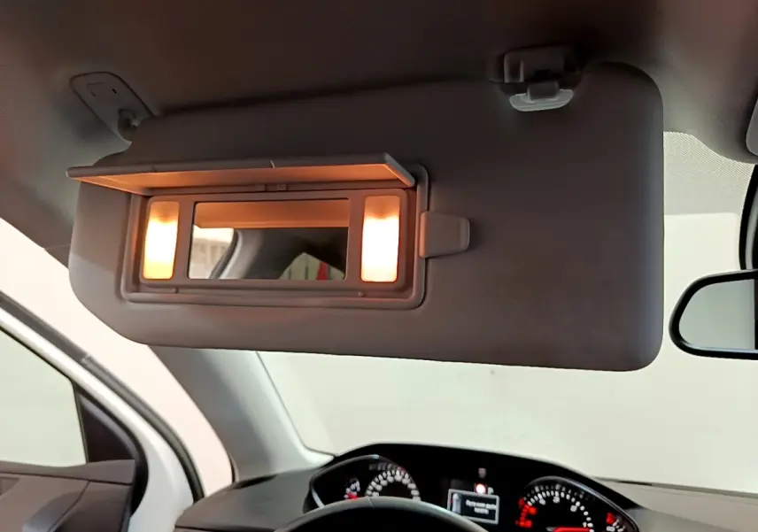 Détail intérieur du pare-soleil côté conducteur avec miroir éclairé, tableau de bord et volant Peugeot 308 visibles en arrière-plan.