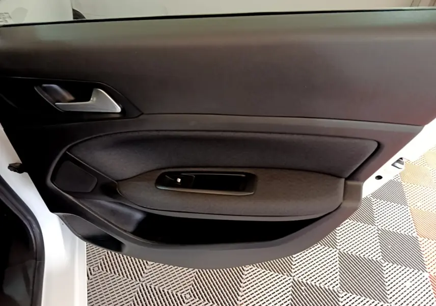 Vue rapprochée de la porte avant gauche blanche de la Peugeot 308 avec garniture noire et poignée argentée.