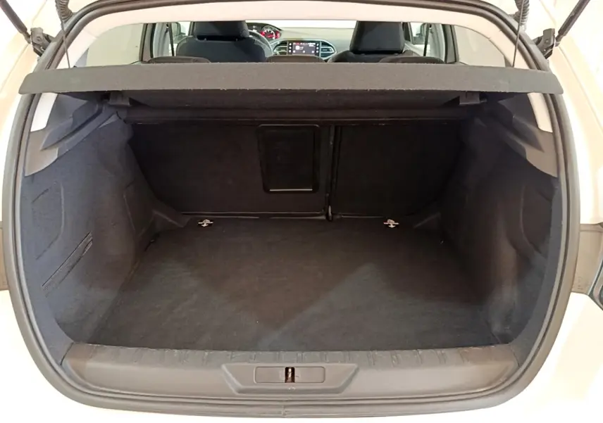Coffre ouvert d’une Peugeot 308 blanche, vue arrière montrant l’espace de chargement et la trappe à ski au fond.