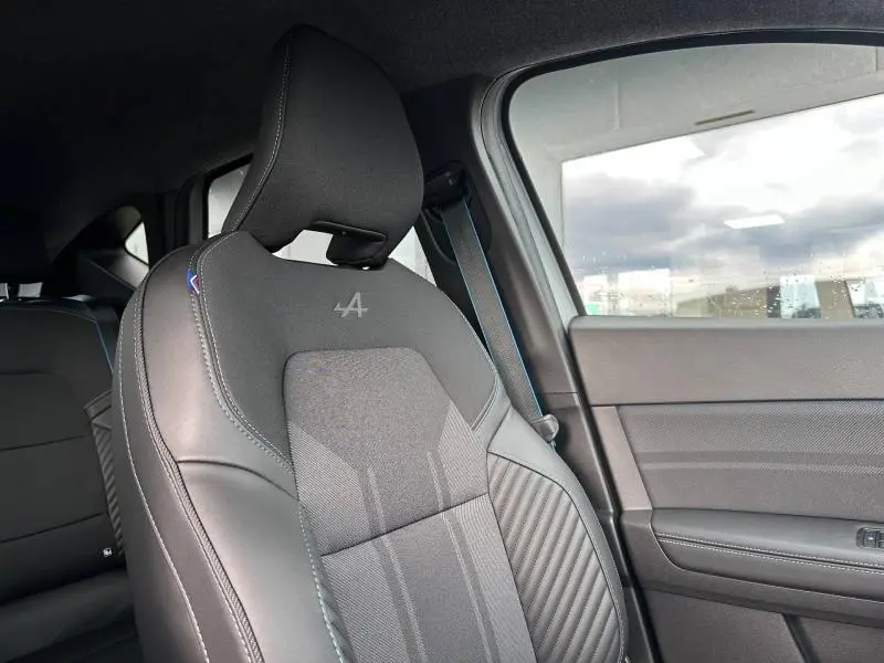 Gros plan sur le siège avant gauche du Renault Captur 2026 esprit Alpine, cuir noir avec surpiqûres bleues et logo Alpine brodé.