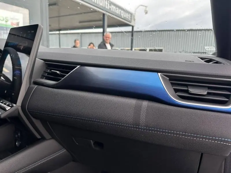 Tableau de bord intérieur du Renault Captur 1.8 E-Tech 2026, vue côté passager avec insert bleu et finition tissu noire.