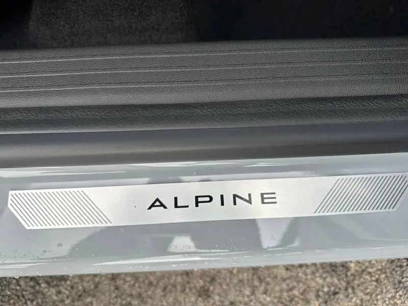 Détail de la plaque Alpine sur le seuil de porte d’un Renault Captur Gris Rafale/Noir Étoilé, version hybride 2026.