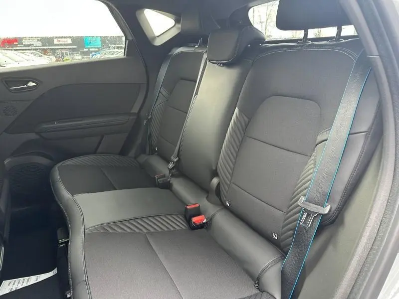 Vue intérieure côté droit des sièges arrière noirs du Renault Captur 1.8 E-Tech hybride 2026 avec surpiqûres bleues.