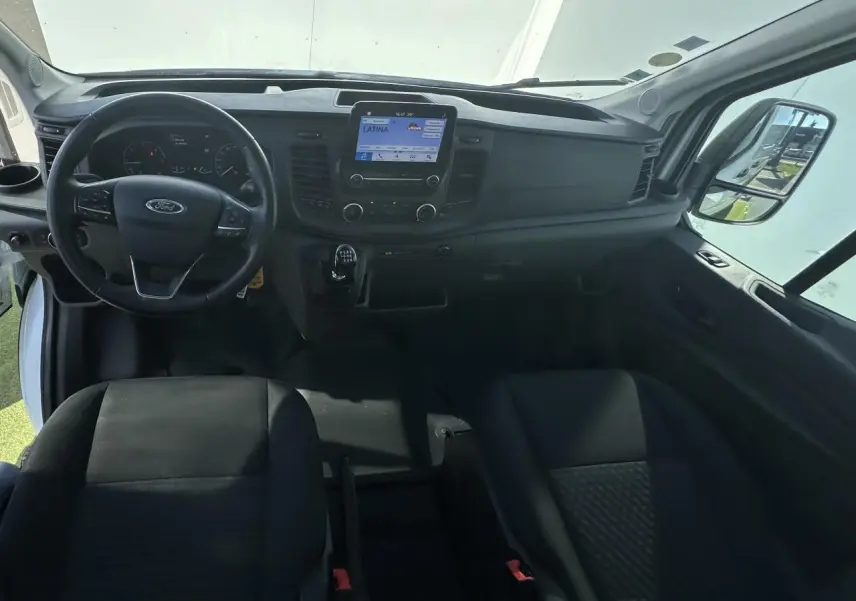 Vue intérieure avant du Ford Transit Fourgon blanc 2020, tableau de bord avec écran tactile et volant multifonction.