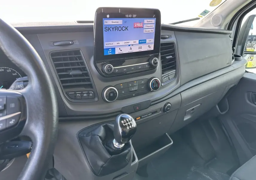 Intérieur du Ford Transit Fourgon 2020, vue du tableau de bord avec écran tactile et levier de vitesses manuel en premier plan.