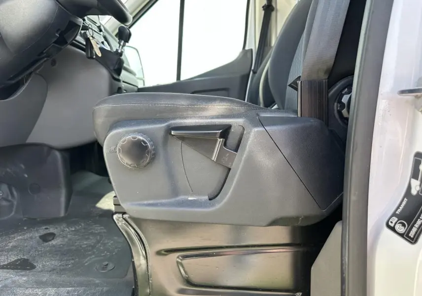 Gros plan sur le siège conducteur noir du Ford Transit Fourgon blanc, avec réglages manuels visibles côté gauche.
