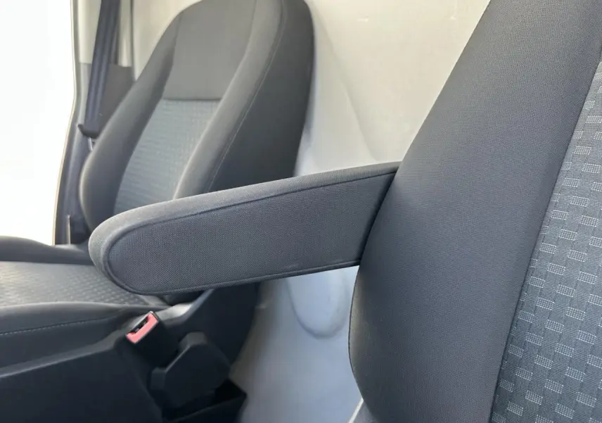 Gros plan sur les sièges avant gris foncé du Ford Transit Fourgon blanc, avec accoudoir relevable côté droit.
