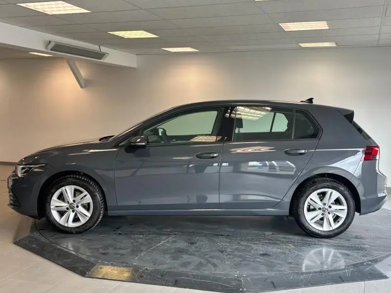 Profil côté gauche d'une Volkswagen Golf 2024 gris dauphin métallisé dans un showroom intérieur lumineux.