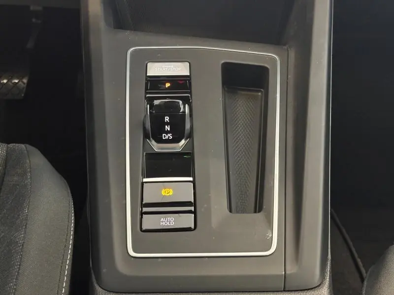 Vue rapprochée de la console centrale grise avec levier de vitesses automatique et bouton de frein à main sur Volkswagen Golf 2024.