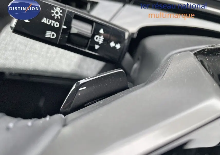 Détail de la commande des feux et palette de changement de vitesse sur le volant d'un Peugeot 3008 noir perle métal hybride 2025.