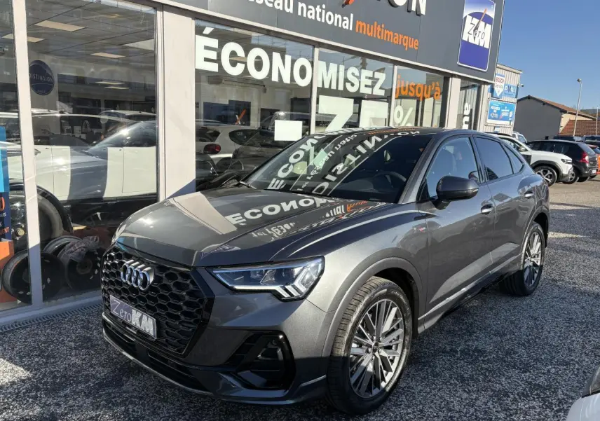 Audi Q3 Sportback gris Daytona en 3/4 avant droit avec calandre noire et jantes 20 branches contrastées.