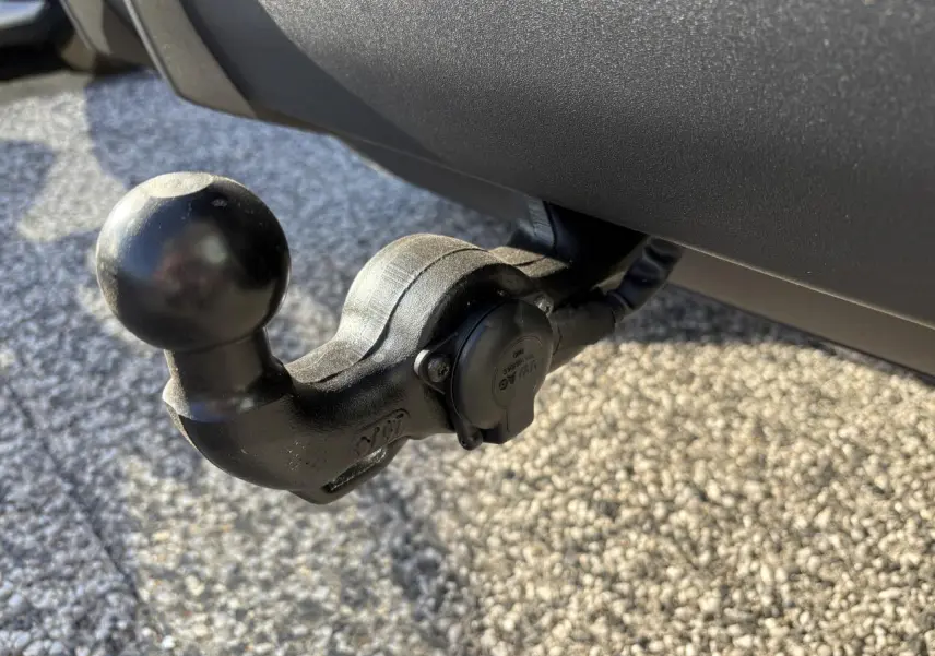 Gros plan sur le crochet d'attelage noir fixé à l'arrière d'un Audi Q3 Sportback gris Daytona.