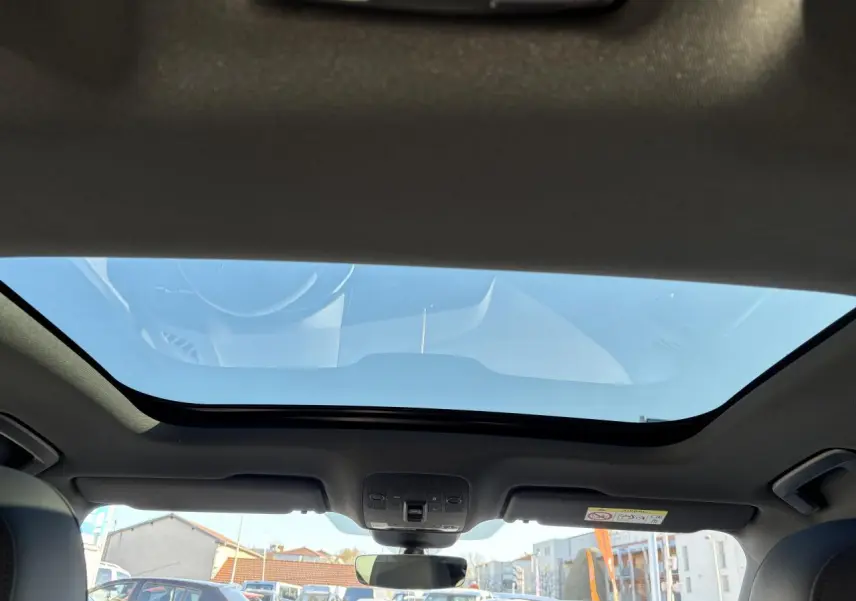 Vue intérieure du toit ouvrant panoramique du SUV Audi Q3 Sportback gris Daytona, avec ciel bleu visible à travers le verre.