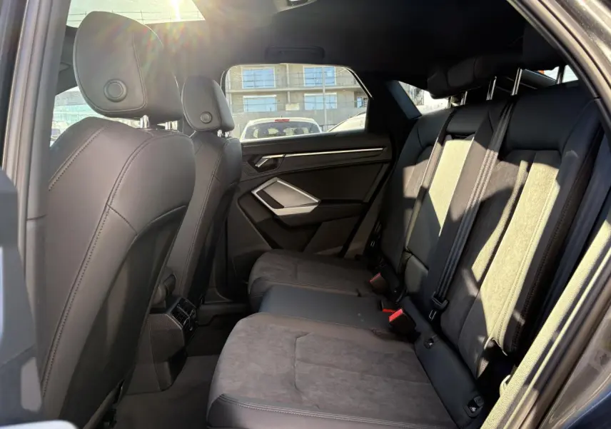 Vue intérieure côté droit des sièges arrière en tissu et cuir gris foncé de l'Audi Q3 Sportback 2025.