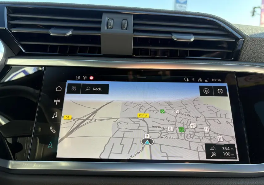 Écran tactile central affichant la navigation GPS dans l'habitacle noir de l'Audi Q3 Sportback gris Daytona.