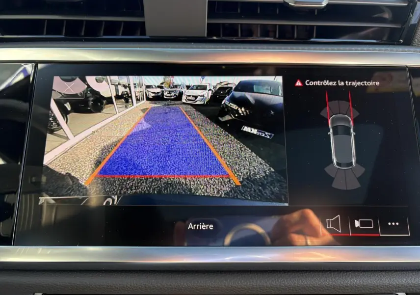 Écran de caméra de recul de l'Audi Q3 Sportback gris Daytona montrant la zone de stationnement avec alertes trajectoire.