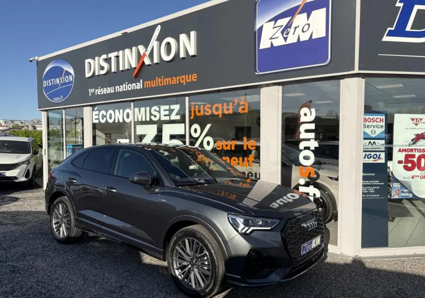 Audi Q3 Sportback gris Daytona vue 3/4 avant droit avec jantes 20 branches et calandre noire devant un showroom