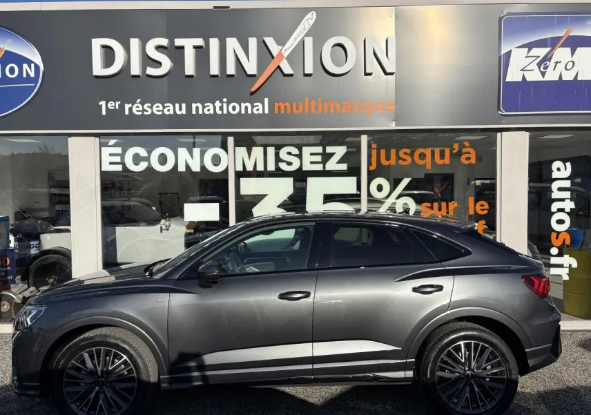 Profil droit d'un Audi Q3 Sportback gris Daytona avec jantes 20 branches en V et badge S line visible sur l'aile avant.
