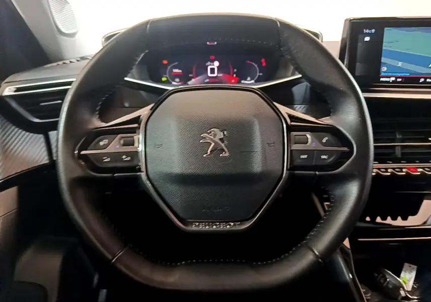 Volant cuir noir de Peugeot 2008 2021 avec commandes intégrées et tableau de bord numérique en arrière-plan.