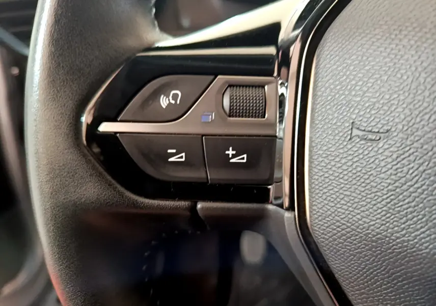 Gros plan sur les commandes gauche du volant cuir noir du Peugeot 2008 gris clair, version PureTech 130 S&S Allure Business.