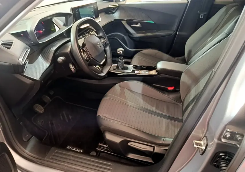 Intérieur côté conducteur du Peugeot 2008 gris clair 2021, volant cuir, tableau de bord numérique et boîte manuelle.