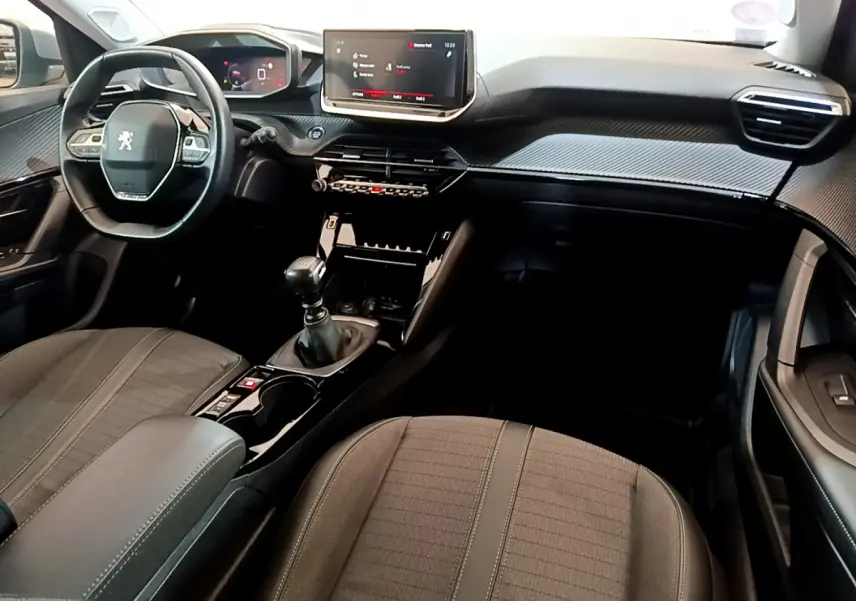 Intérieur du Peugeot 2008 gris clair, vue avant centrée sur tableau de bord, volant cuir et écran tactile 10 pouces.
