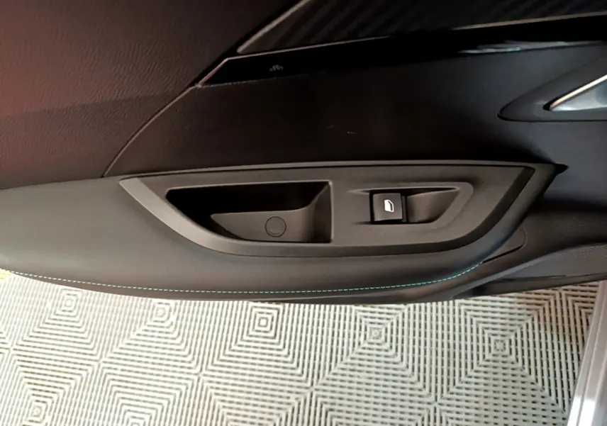 Détail de la poignée intérieure côté gauche d'une Peugeot 2008 gris clair avec bouton de verrouillage.
