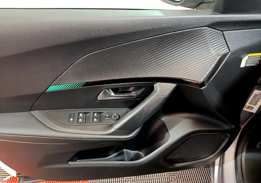 Vue intérieure côté conducteur de la porte gris clair du Peugeot 2008 avec commandes de vitres et insert effet carbone.
